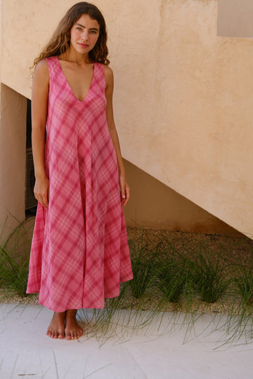 Presenting the Deep-Wine Checkered Midi Dress, a retro-inspired creation by Audrey E Leary and World of Crow. This dress boasts playful pink checks, a flattering V-neckline, and a chic midi length. Made from exceptionally lightweight, hand-woven cotton, it offers a soft touch and excellent breathability for effortless everyday wear