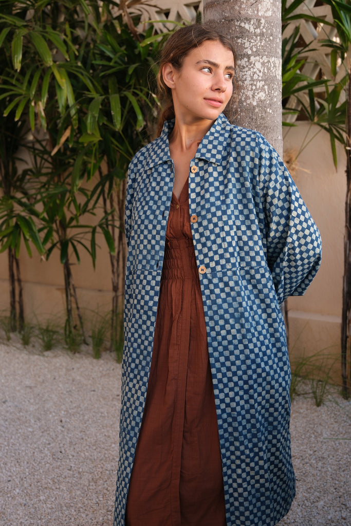 Presenting the Indigo Checkered Duster Jacket, a versatile wardrobe essential made from handwoven cotton. With its classic indigo and white checkered pattern, straight collar, coconut buttons, and relaxed fit, it’s perfect for layering over both dressy and casual outfits..