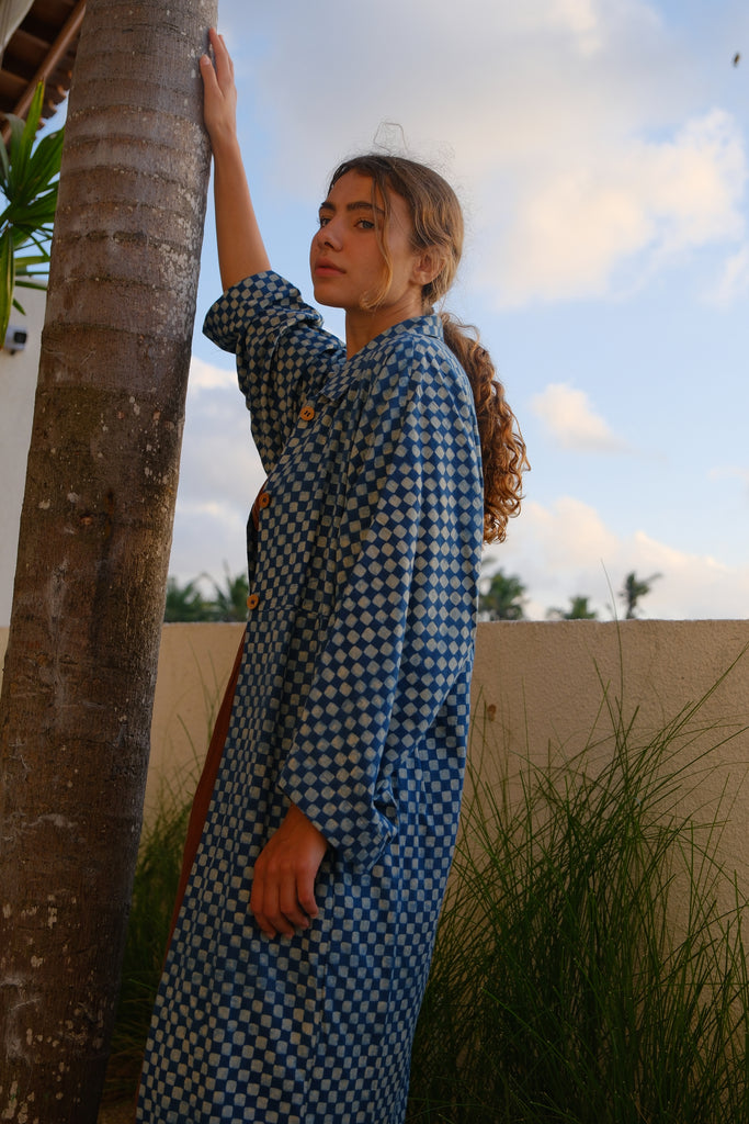 Presenting the Indigo Checkered Duster Jacket, a versatile wardrobe essential made from handwoven cotton. With its classic indigo and white checkered pattern, straight collar, coconut buttons, and relaxed fit, it’s perfect for layering over both dressy and casual outfits..