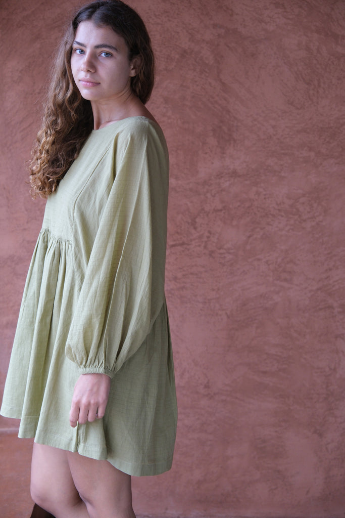 Presenting the Olive Get Away Dress, a collaboration between Audrey E Leary and World of Crow. This unique olive green mini dress features a scoop neckline, three-quarter puff sleeves, and is made from soft, handwoven cotton, offering a breathable, comfortable fit ideal for daily wear.