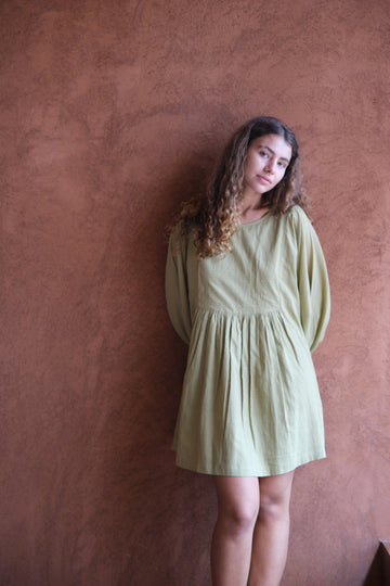 Presenting the Olive Get Away Dress, a collaboration between Audrey E Leary and World of Crow. This unique olive green mini dress features a scoop neckline, three-quarter puff sleeves, and is made from soft, handwoven cotton, offering a breathable, comfortable fit ideal for daily wear.