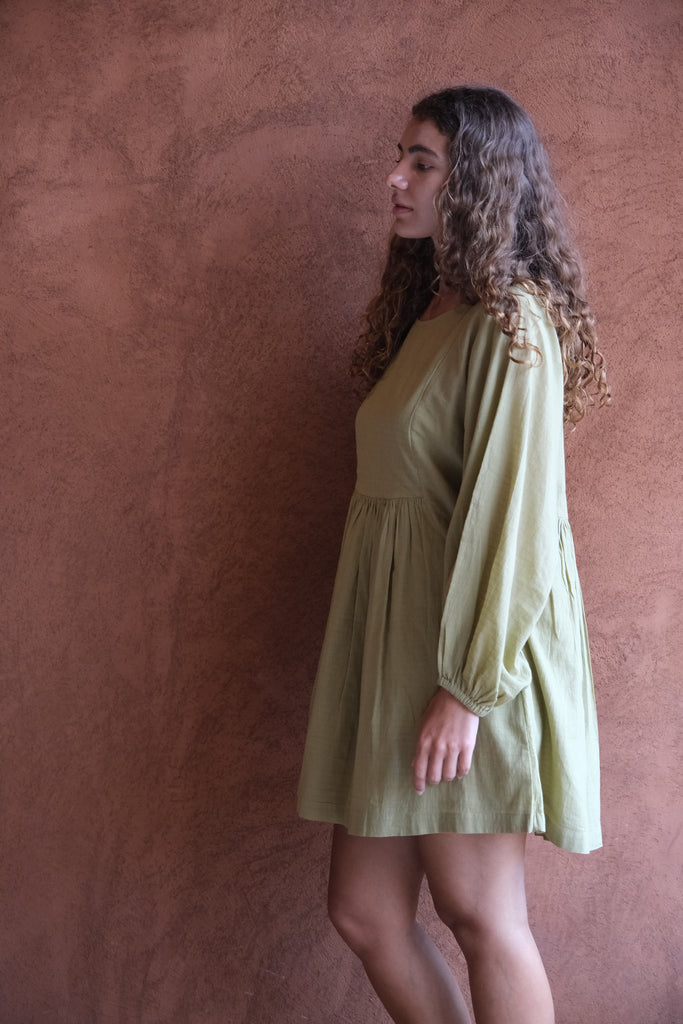 Presenting the Olive Get Away Dress, a collaboration between Audrey E Leary and World of Crow. This unique olive green mini dress features a scoop neckline, three-quarter puff sleeves, and is made from soft, handwoven cotton, offering a breathable, comfortable fit ideal for daily wear.