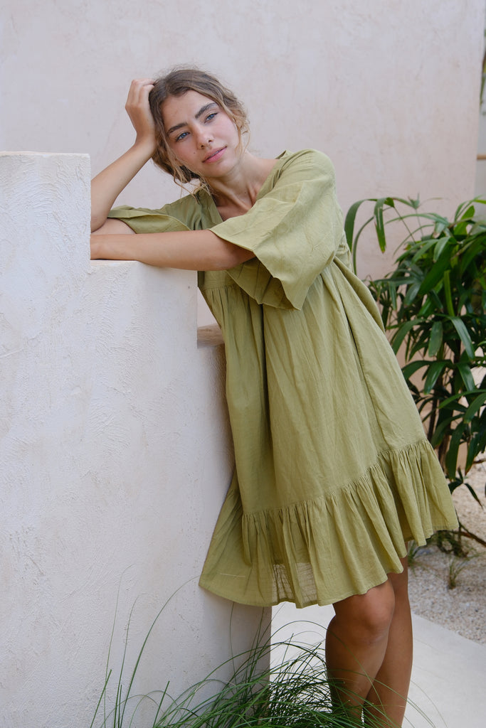 Presenting the Olive Green Day Dress, a collaboration between Audrey E Leary and World of Crow. This mini dress features a V-neck, drop shoulders, and a distinctive olive green shade. Crafted from soft, handwoven cotton, it provides a comfortable, lightweight fit ideal for daily wear.