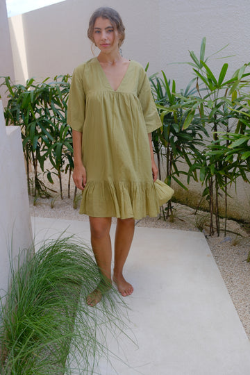 Presenting the Olive Green Day Dress, a collaboration between Audrey E Leary and World of Crow. This mini dress features a V-neck, drop shoulders, and a distinctive olive green shade. Crafted from soft, handwoven cotton, it provides a comfortable, lightweight fit ideal for daily wear.