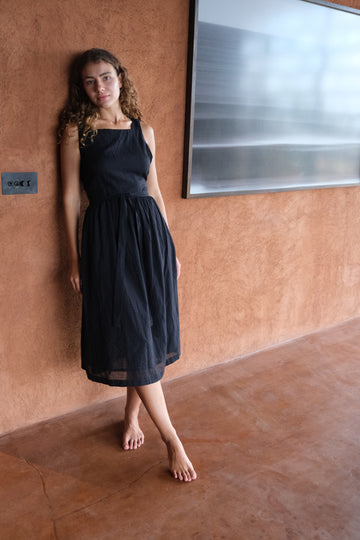 Presenting The Classic Hitch Dress, a sleek collaboration between Audrey E Leary and World of Crow. This black midi dress features a square neckline, wrap-around design with a drawstring waist, and a comfortable, true-to-size fit in soft, lightweight fabric.