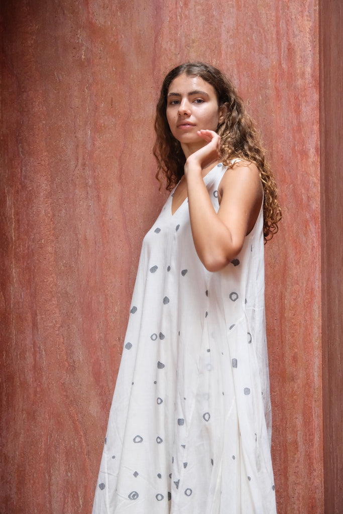 Presenting the Holiday Slip Dress, a joint creation by Audrey E Leary and World of Crow. This off-white midi dress, adorned with charming polka dots, is crafted from soft, handwoven Jamdani cotton. Its sleeveless, lightweight design makes it ideal for layering and versatile styling, combining elegance with practicality.