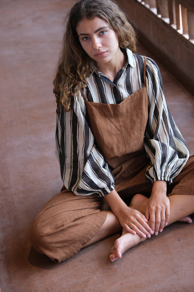 Presenting the Jane Austen Shirt from the Audrey X Crow Collection, stylishly worn by a woman in overalls. Sitting on the floor, she effortlessly highlights the shirt’s classic design and exquisite craftsmanship.