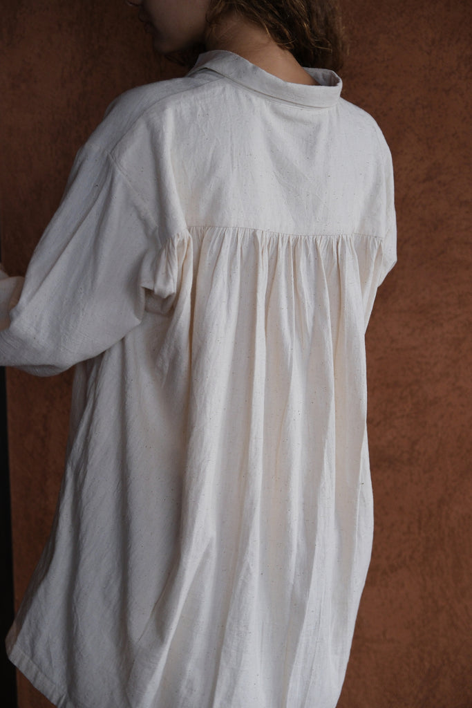 Presenting the White Artist Smock, a collaboration between Audrey E Leary and World of Crow. Made from thick, handwoven organic cotton, this short smock features a straight collar, puffed full sleeves, and gathered cuffs, with spacious pockets and a comfortable fit ideal for painting, crafting, and travel.