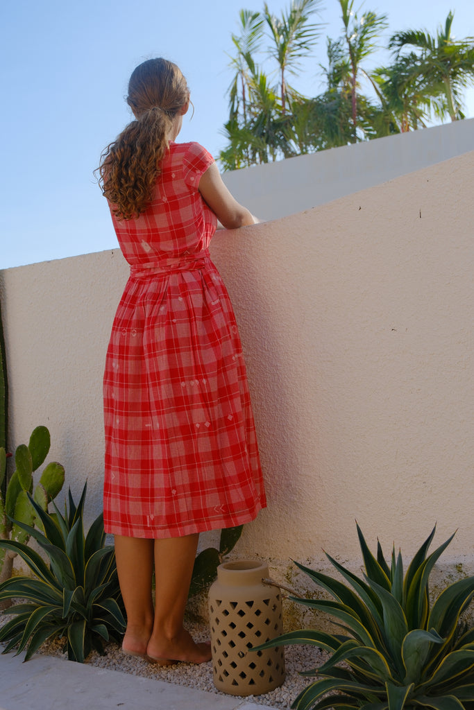 Presenting the Audrey Dress, a stunning creation from Audrey E Leary and World of Crow. This vibrant red wrap-style midi dress boasts a chic V-neck and cap sleeves, crafted from soft, handwoven cotton. Sustainably made, it combines elegance and comfort, delivering a distinctive and stylish appearance