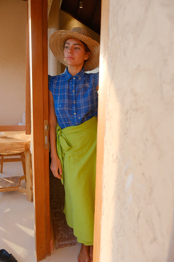 Experience effortless sophistication with our vibrant parrot green wrap skirt, crafted from handwoven cotton. Showcased on a model with a chic hat, this summer-ready midi-length piece blends style with sustainability, making it perfect for eco-conscious fashion enthusiasts.