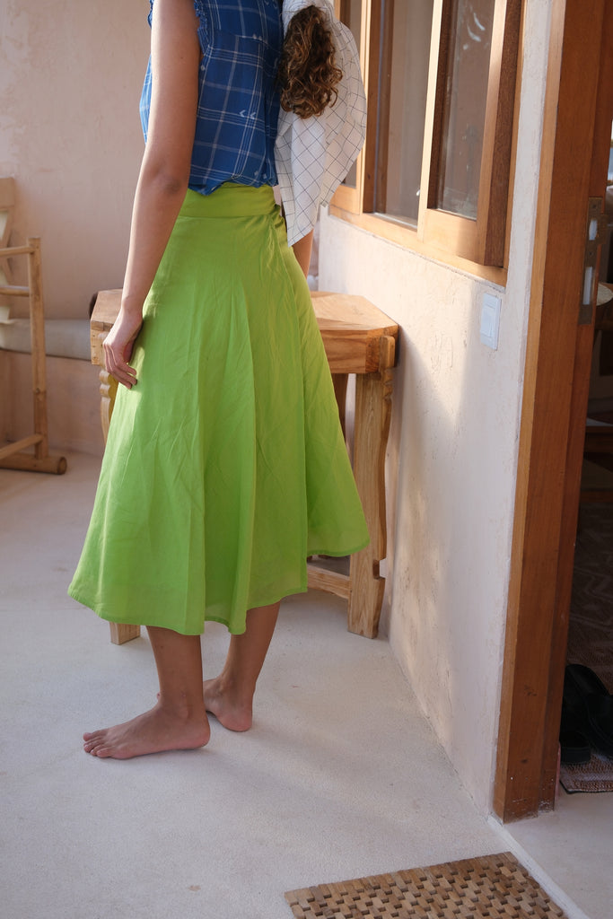 Experience effortless sophistication with our vibrant parrot green wrap skirt, crafted from handwoven cotton. Showcased on a model with a chic hat, this summer-ready midi-length piece blends style with sustainability, making it perfect for eco-conscious fashion enthusiasts.